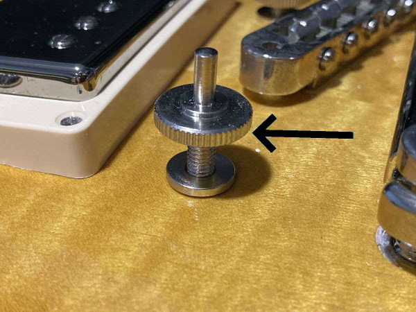 Gibson Nashville bridge post and thumbwheel threaded into a metal body bushing, side view